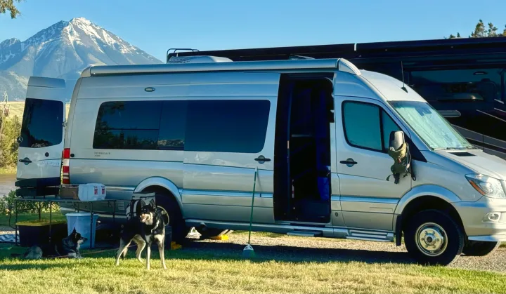 Silver camper van with dogs, mountain views, and an outdoor setup, perfect for an RV rental adventure.. Airstream Interstate 2017