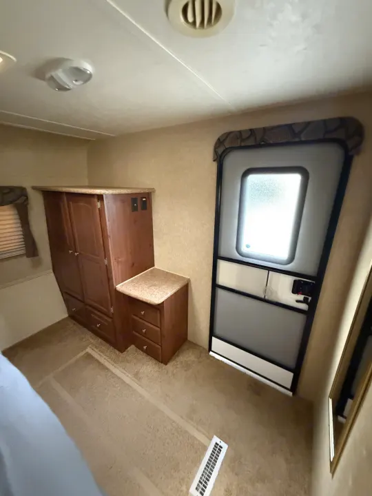 Cozy interior of an RV rental, featuring wood cabinets, a door, and carpeted floor, offering comfortable living space.. Rockwood Signature Ultra Lite 2012