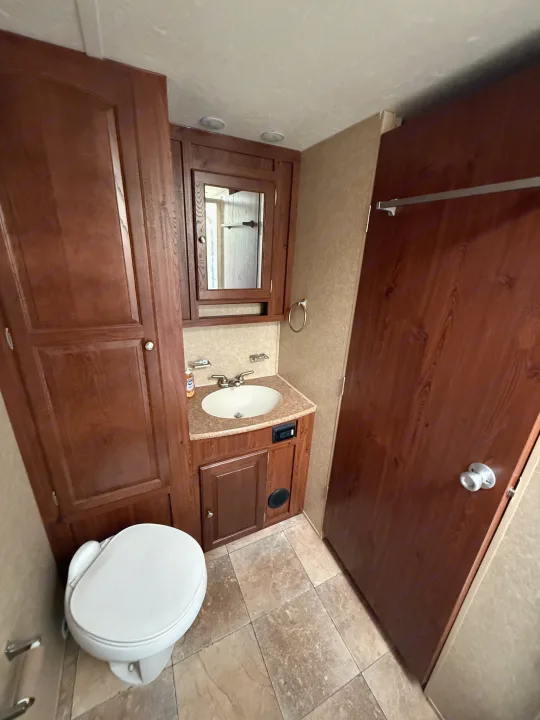 RV rental: Clean, modern bathroom with a white toilet, wooden vanity, sink, mirrored cabinet, and tiled floor.. Rockwood Signature Ultra Lite 2012