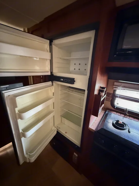 This RV rental kitchen has an open, empty fridge with a freezer, microwave, and cooktop, ideal for your trip.. Rockwood Signature Ultra Lite 2012