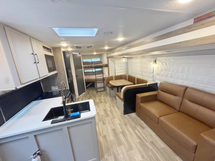 Step inside this RV rental: a bright, spacious interior with a modern kitchen, U-shaped dinette, bunks, and sofa.. Forest River Vibe Remote 2024