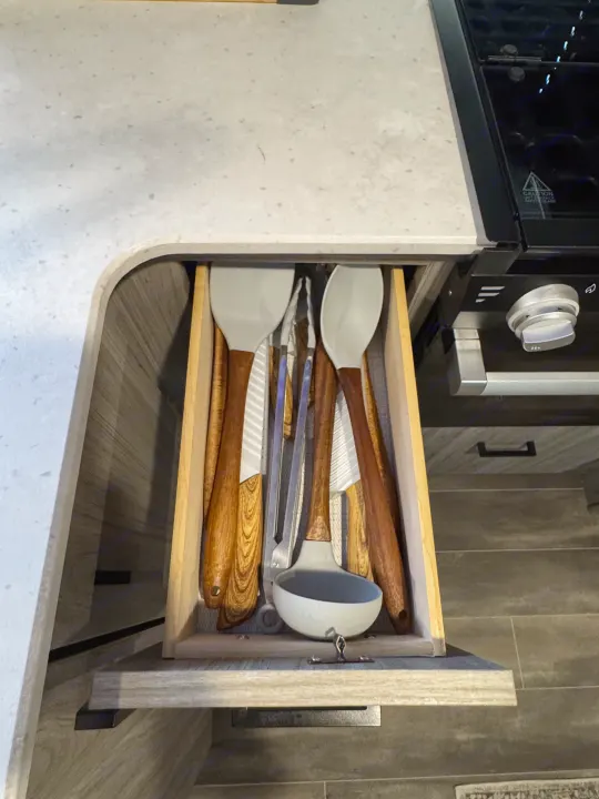 Well-equipped rv rental kitchen drawer: spatulas, tongs, knives, and ladle ready for travel cooking.. Keystone RV Passport TT 2022