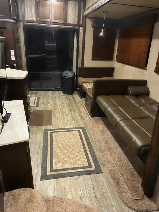 This RV rental's interior boasts a comfortable leather sofa, wood-look flooring, cabinets, and an adjoining rear garage access.. Forest River Wolf Pack 2018
