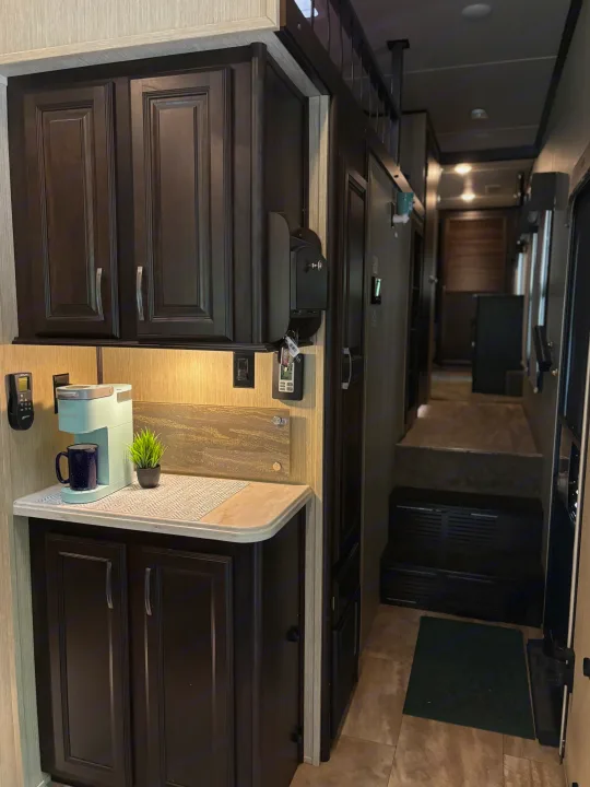 Modern RV rental interior: Kitchenette with coffee maker, dark cabinets, and steps leading to a hallway. Great for RV travel!. 4x4fcmp23h6007284 Columbus 2017