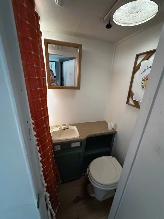 Compact RV rental bathroom with sink, mirror, toilet, and shower curtain. Perfect for travel!. Jayco Jay Flight 2008