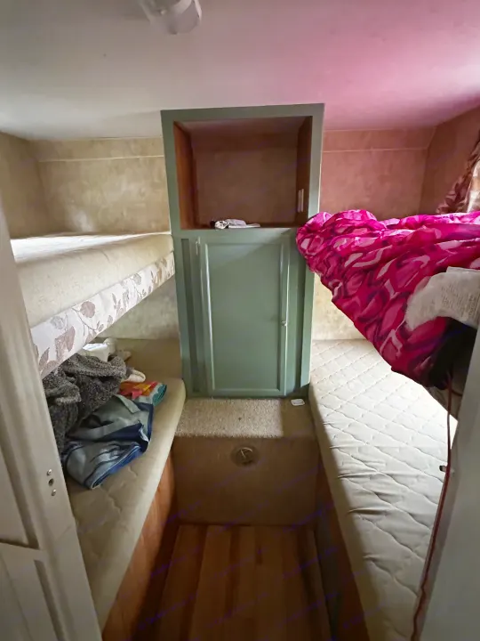 Experience the practical interior of this RV rental, featuring bunk beds, a main bed with a vibrant blanket, and a central cabinet.. Jayco Jay Flight 2008
