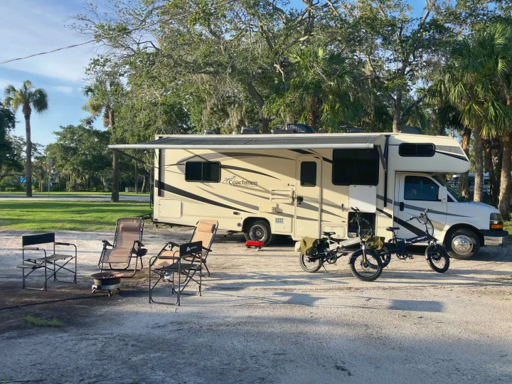 Spacious rv rental motorhome at a sunny campground with chairs, fire pit, and e-bikes, ready for outdoor adventure.. Forest River Coachmen Freelander 2017