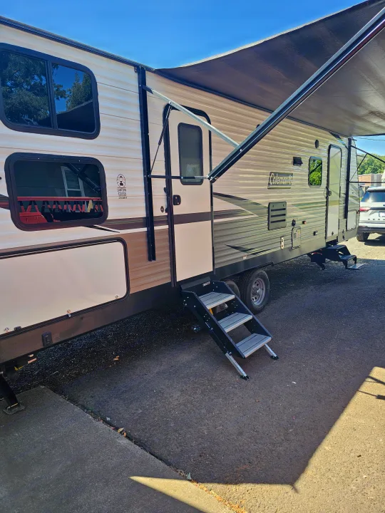 Coleman travel trailer RV rental parked with awning extended & entry steps down. Ready for adventure, offering comfortable travel & camping.. Dutchmen Coleman Lantern 2021