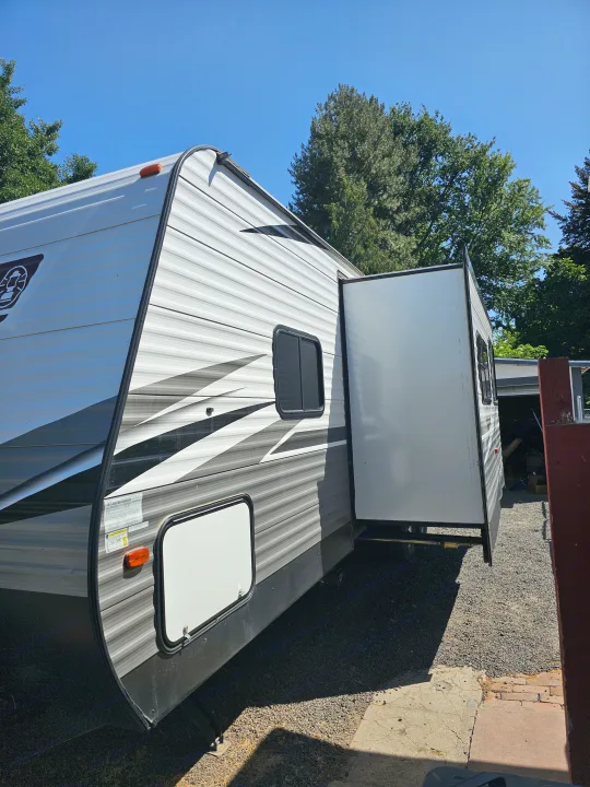 Spacious RV rental: A white and gray travel trailer with an extended slide-out, parked outdoors on a sunny day.. Dutchmen Coleman Lantern 2021