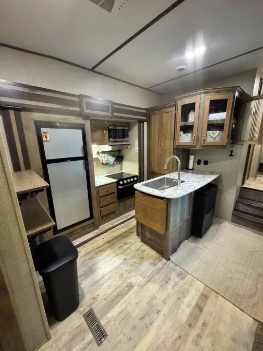 Inside an RV rental: a well-equipped kitchen with modern appliances, ample storage, and steps leading to another level.. Keystone RV Sprinter Campfire Edition 2020