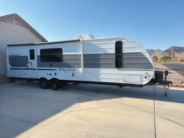 A white and gray Salem Cruise Lite RV rental travel trailer parked on a concrete driveway under a clear sky.. Forest River Salem Cruise Lite 26ICE 2025