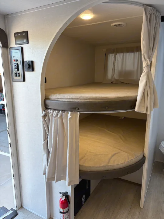 RV rental interior with stacked bunk beds in an arched alcove. Features privacy curtains, control panel, and ambient lighting.. Forest River Salem Cruise Lite 26ICE 2025