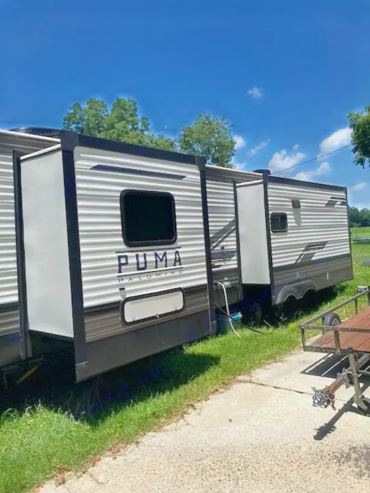 PUMA Palomino RV rental: A large, grey travel trailer with extended slide-outs, parked on grass and concrete outdoors.. Forest River Puma 2023