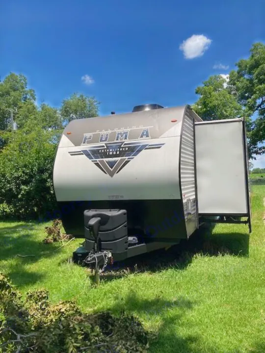 Puma travel trailer for rv rental, parked on grass under a blue sky. Ready for your outdoor adventure.. Forest River Puma 2023