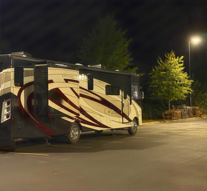 Sleek RV rental with unique dark and light patterns parked at night in a well-lit lot, ready for adventure.. Coachmen Encore 2022