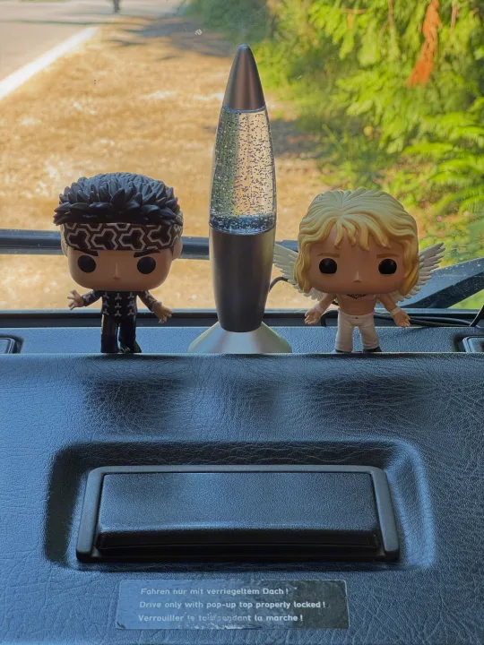 Funko Pops and a glitter lamp adorn an RV rental dash. A "pop-up top" warning sticker suggests unique vehicle travel.. Volkswagen T3 Westfalia 1987