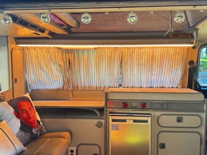 Unique RV rental interior with fun disco balls, kitchenette, and cozy seating. Ideal for distinctive travel.. Volkswagen T3 Westfalia 1987