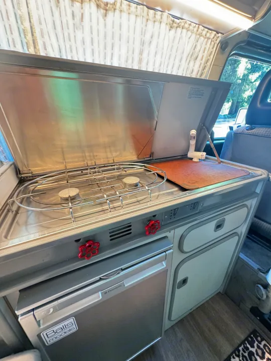 RV rental: Inside a camper's compact kitchen, featuring a two-burner stove, sink, & Dometic refrigerator.. Volkswagen T3 Westfalia 1987