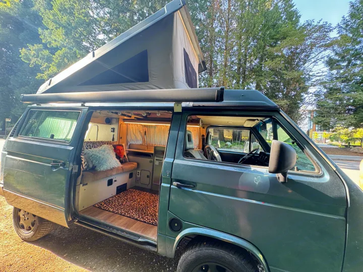 Open for adventure! This unique pop-top camper van with its open door reveals a spacious and inviting interior for RV rental.. Volkswagen T3 Westfalia 1987
