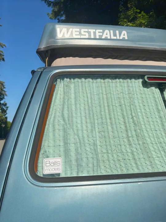 Vintage blue Westfalia camper van, perfect for rv rental adventures. Features pop-top roof & patterned rear window curtains.. Volkswagen T3 Westfalia 1987