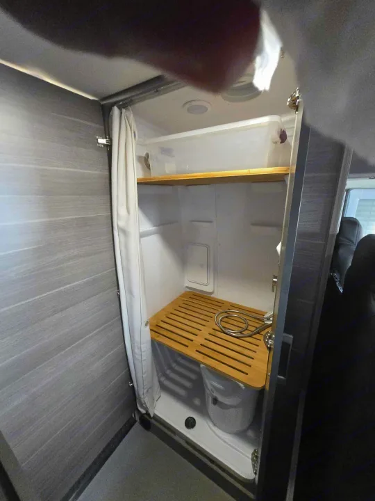 This RV rental features a compact shower with a bamboo slatted mat, bucket, and overhead storage bin.. Entegra Launch Sprinter High Roof AWD 4x4 Camper Van 2025