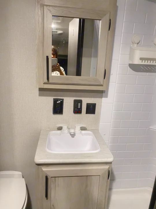 RV rental bathroom with a sink, mirror, toilet, and tiled shower. Reflects efficient space usage.. KZ Escape 2021