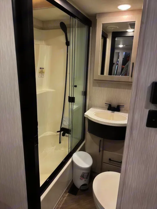 Compact RV rental bathroom features a modern shower, sink vanity, and toilet, designed for efficiency.. Heartland Cyclone 2022