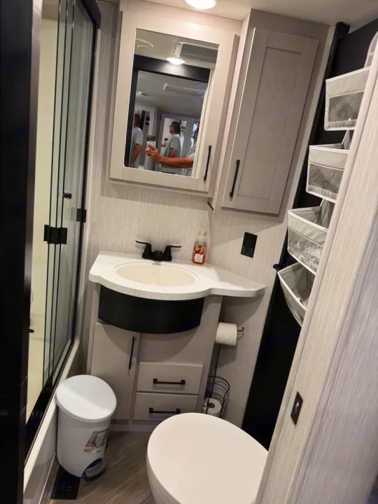 Modern RV rental bathroom: compact design with sink, toilet, and shower. Ideal for comfortable travel.. Heartland Cyclone 2022