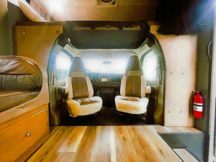 Spacious RV rental interior with front cabin view, wooden flooring, built-in bed, and safety features. Perfect for travel adventures!. Coachmen Leprechaun 2016