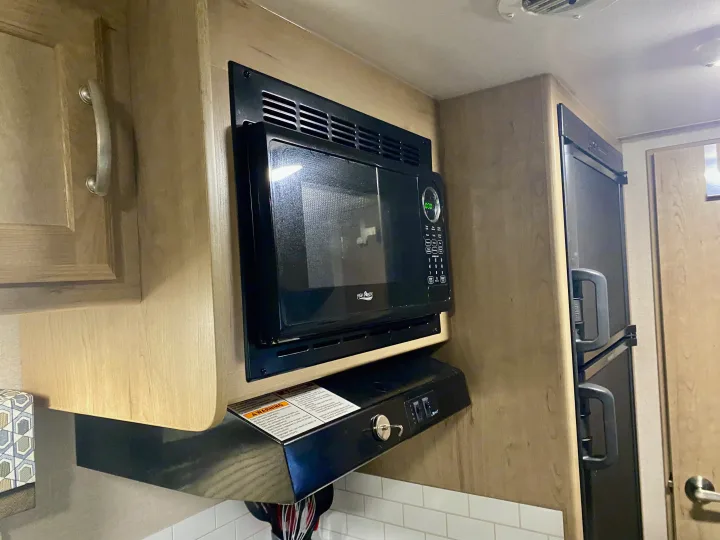 Appliances in an RV rental: a black High Pointe microwave, range hood, and refrigerator.. Winnebago Minnie Winnie 2020