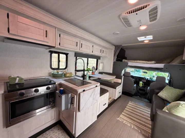 Modern RV rental interior featuring a bright kitchen, dinette, living area, and over-cab bunk bed space for travelers.. Forest River ENTRADA 3100FB 2024