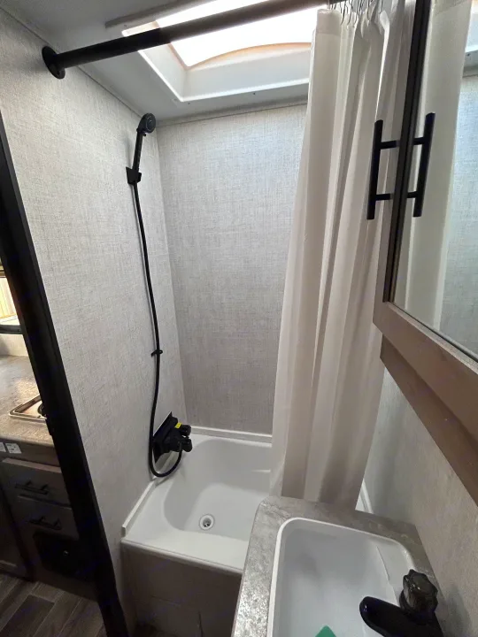 RV rental bathroom features compact shower/tub with a skylight, curved rod, and sink. Ready for your travels.. Gulf Stream Ameri-Lite 2022