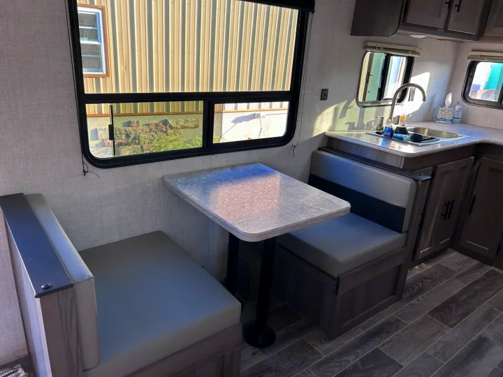 Spacious RV rental interior featuring a bright dinette with comfy benches and a compact kitchen area with a sink and cabinets.. Gulf Stream Ameri-Lite 2022
