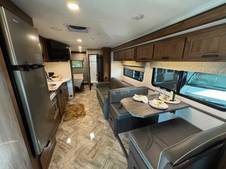 Inside a cozy RV rental: modern kitchen, comfortable dinette with set table, and spacious living area. Perfect for travel.. Forester LE 2022