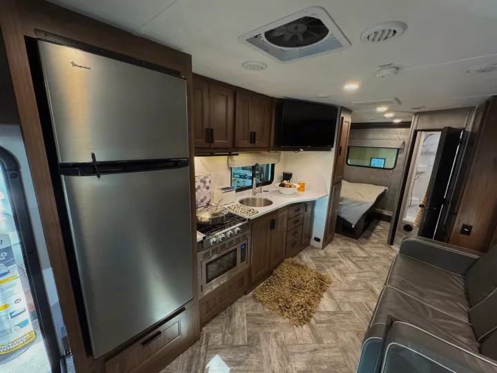 Spacious and modern RV rental interior featuring a full kitchen, comfortable sofa, and bedroom. Perfect for your next adventure!. Forester LE 2022