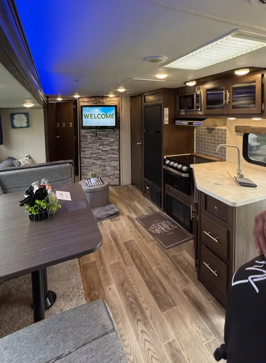 Modern RV rental interior with a welcoming living area, full kitchen, and dining space. Blue ceiling lights add ambiance.. Forest River Cherokee Grey Wolf 2019