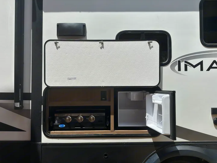 RV rental with an outdoor kitchen, featuring a griddle and mini-fridge. Perfect for camping adventures.. Grand Design Imagine 2023
