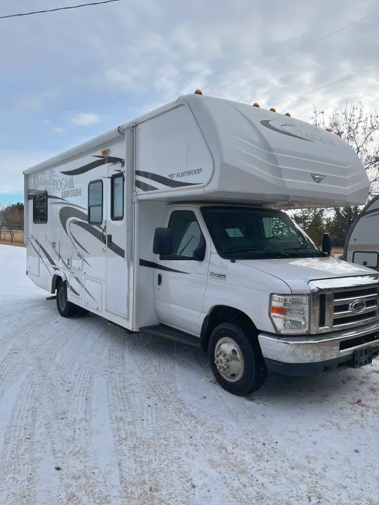 White Class C Fleetwood Tioga Montana RV rental parked on a snowy road under an overcast sky.. Tioga Montara 2012
