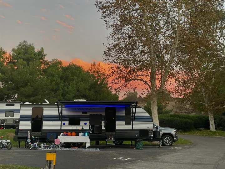 A serene RV rental campsite scene with an inviting outdoor living area, glowing under a beautiful sunset.. Forest River Cherokee Grey Wolf 2021