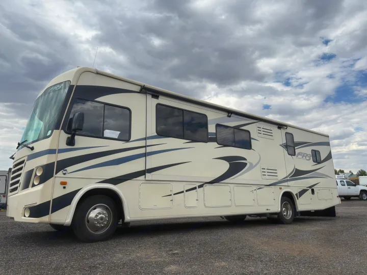 A cream and black FR3 motorhome, ideal for RV rental travel, parked on a gravel lot under an overcast sky.. Forest River FR3 2019