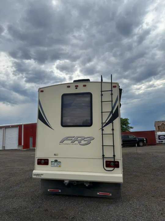 Rear view of an RV rental parked on gravel under a cloudy sky. Perfect for your next motorhome adventure.. Forest River FR3 2019