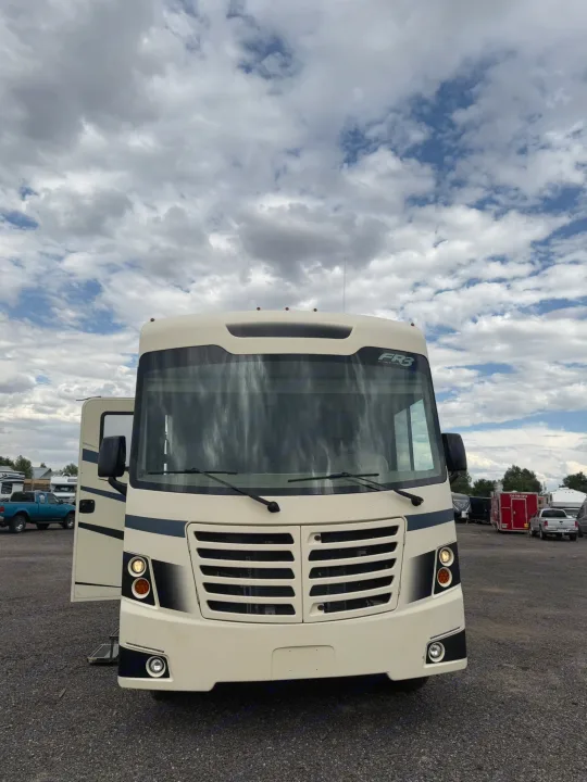 This large, cream-colored FR3 Class A motorhome, ready for RV rental, is pictured from the front with its side door open.. Forest River FR3 2019