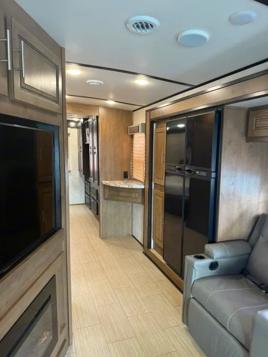 Modern RV rental interior with spacious living area, comfy recliner, entertainment center, and full kitchen.. Forest River FR3 2019