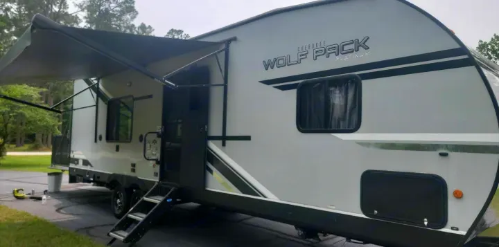 Gray Cherokee Wolf Pack travel trailer RV, featuring an extended awning and steps. Perfect for your next rv rental adventure.. Forest River Cherokee Wolf Pack 2021
