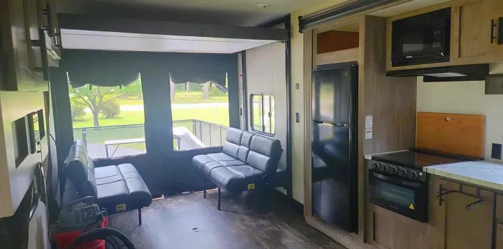 Spacious rv rental interior showing a kitchen, appliances, and convertible seating/garage area with an open rear ramp view.. Forest River Cherokee Wolf Pack 2021