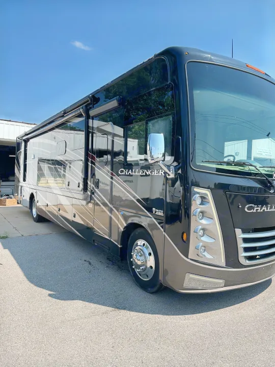 A large, modern black and grey Challenger RV/motorhome parked outdoors. Ideal for an RV rental or a luxurious travel experience.. Thor Challenger 2022