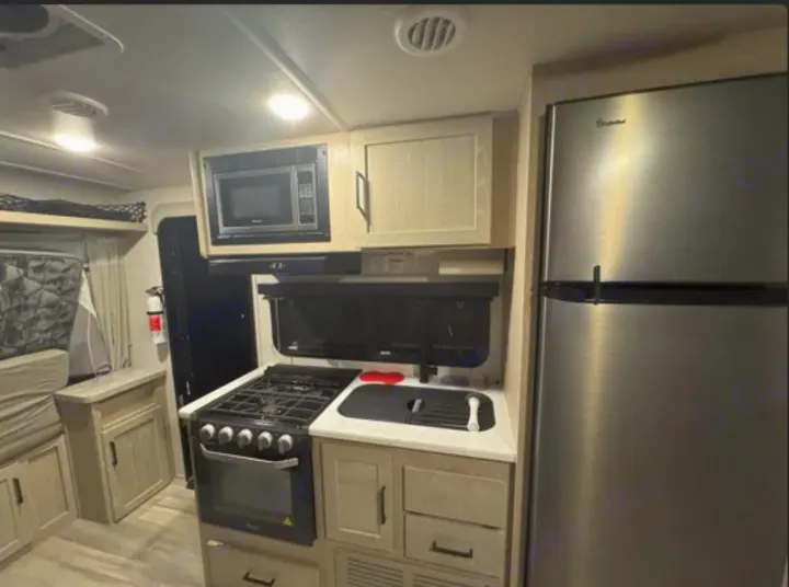 Inside this **RV rental**, discover a bright, modern kitchen with a stainless steel fridge, microwave, oven, and sink area.. Rockwood Roo 2022