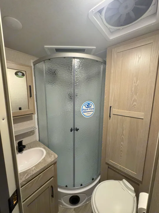 Compact RV rental bathroom featuring a curved shower, sleek sink, and toilet for comfortable travels.. Rockwood Roo 2022