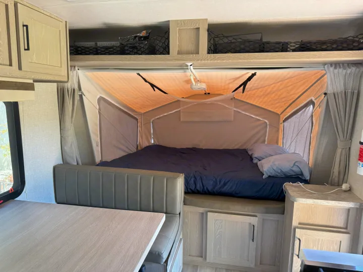 Experience comfort in this RV rental's interior with a pop-up bed, dinette, and overhead storage.. Rockwood Roo 2022
