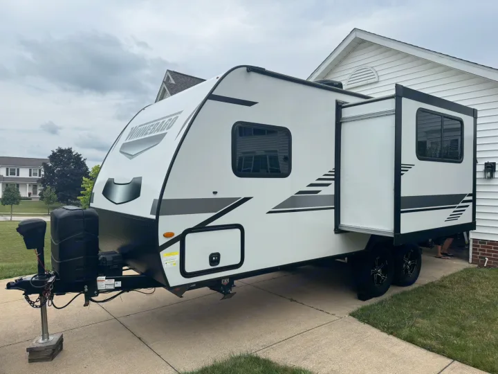 White Winnebago travel trailer, a great RV rental option, parked on a driveway with its side slide-out extended.. Minnie Micro Minnie 2021